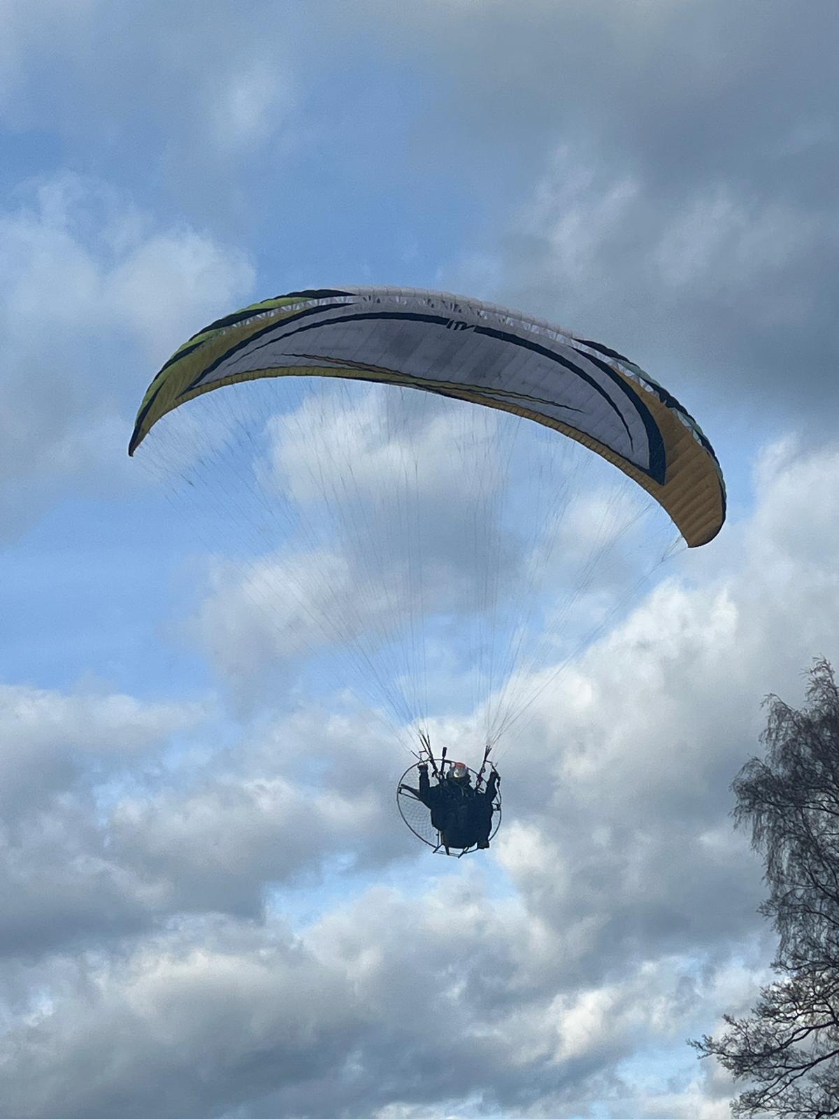 51eef93b-1d4e-4b3b-9bad-a8d107b5762b Two paragliders soaring at golden hour above hills