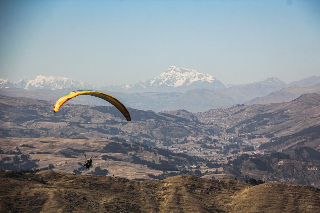 Paraglider flying over a mountainous landscape