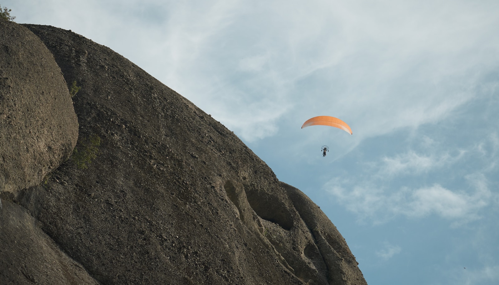 Paraglider over rocky cliff Paraglider flying over a rocky cliff