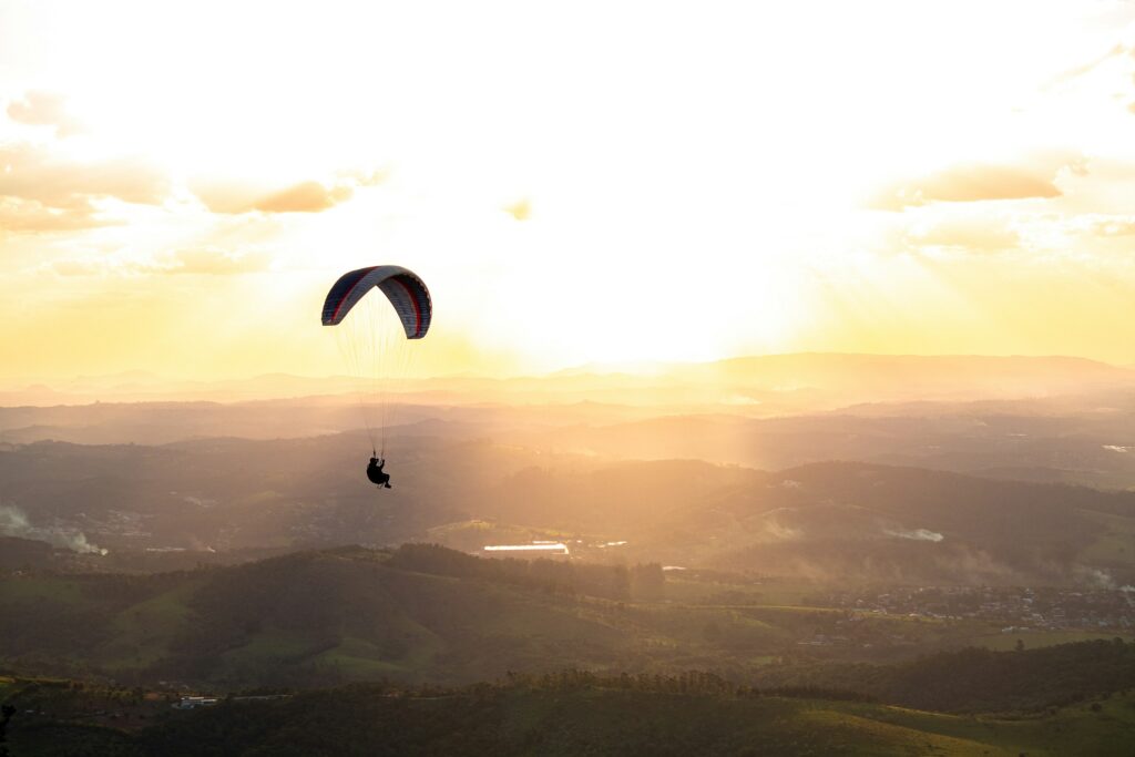 Solitary paraglider above breathtaking sunset mountain panorama